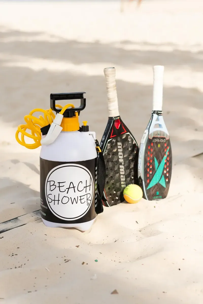 Ducha ao lado de raquetes de beach tennis na areia